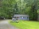 Charming single-story home with blue siding, flower boxes and lush green lawn surrounded by mature trees at 1634 Hurdle Mills Rd, Roxboro, NC 27574
