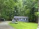 Charming single-story home with blue siding, flower boxes and lush green lawn surrounded by mature trees at 1634 Hurdle Mills Rd, Roxboro, NC 27574