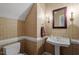 Elegant powder room with decorative wallpaper, pedestal sink, and ornate sconces at 1703 Berwickshire Cir, Raleigh, NC 27615
