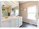 Bathroom with double vanity, framed mirrors, and large window at 1816 Piperwood Ct, Durham, NC 27713