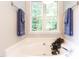 Close up of the bathtub with overhead lighting and two hanging towels at 1816 Piperwood Ct, Durham, NC 27713