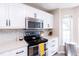 Modern kitchen showcases stainless microwave and range with stylish tile backsplash and white cabinetry at 1816 Piperwood Ct, Durham, NC 27713