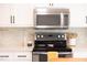 Close up view of modern microwave, stove and mosaic backsplash at 1816 Piperwood Ct, Durham, NC 27713