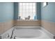 Soaking tub in a light-filled bathroom with tiled walls and decor at 2012 Sterling Hill Dr, Fuquay Varina, NC 27526