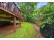 Home's backyard showing a spacious yard with lush greenery, partially shaded by an elevated deck for outdoor living at 203 Lighthouse Way, Cary, NC 27511