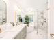 Bright bathroom with double sinks, soaking tub, and glass shower, gold fixtures at 203 Lighthouse Way, Cary, NC 27511
