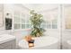 Bright bathroom with white soaking tub, large window, and leafy tree at 203 Lighthouse Way, Cary, NC 27511