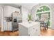 Kitchen with stainless steel refrigerator, white cabinets, center island, eat-in kitchen and view from a large window at 203 Lighthouse Way, Cary, NC 27511