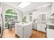 Bright kitchen featuring white cabinetry, an island, stainless steel appliances, and a large window overlooking the backyard at 203 Lighthouse Way, Cary, NC 27511