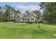 Two-story home with lush green lawn, beautiful landscaping, and a long driveway and mature trees at 205 Sherman Pines Dr, Fuquay Varina, NC 27526