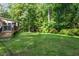 A grassy backyard with trees in the background, and a deck attached to the house at 2410 Overbrook Ln, Sanford, NC 27330
