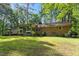 A brick house with a large screened-in porch and a wooden deck, surrounded by lush greenery at 2410 Overbrook Ln, Sanford, NC 27330