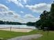 Beach volleyball court with lake view, surrounded by picnic tables, kayaks, and lush greenery at 280 Sagamore Dr, Louisburg, NC 27549