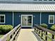 Close up of clubhouse entrance with glass doors, flanked by green bushes, and a concrete walkway at 280 Sagamore Dr, Louisburg, NC 27549