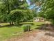 Charming single-story home with a covered porch nestled amongst lush trees and green grass at 280 Sagamore Dr, Louisburg, NC 27549