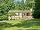 Inviting single-story home with green roof and charming front porch nestled among lush trees at 280 Sagamore Dr, Louisburg, NC 27549