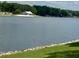 Scenic lake view featuring a sandy beach and community clubhouse in the distance, all lined with green grass at 280 Sagamore Dr, Louisburg, NC 27549