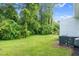 Lush backyard with expansive green space, mature trees, and an air conditioning unit at 313 W Church St, Angier, NC 27501