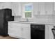 Well-lit kitchen with white cabinets, stainless steel sink, modern backsplash, and black appliances for a sleek design at 313 W Church St, Angier, NC 27501