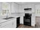 Modern kitchen with white cabinetry, contemporary backsplash, black appliances, and wood-look flooring for cooking at 313 W Church St, Angier, NC 27501