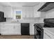 Bright kitchen featuring white cabinets, countertops and backsplash, accented by black appliances and wood-look flooring at 313 W Church St, Angier, NC 27501