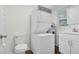 Functional laundry room featuring a toilet, stacked washer/dryer, sink, and water heater for convenience at 313 W Church St, Angier, NC 27501