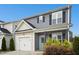 Charming two-story home featuring a white garage door, light green front door and meticulous landscaping at 34 Schoolhouse Way, Clayton, NC 27520
