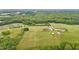 Scenic aerial view of a meticulously maintained property with houses, outbuildings, lush lawns, and forest at 3465 Covington Trl, Mebane, NC 27302