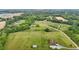 Aerial view of a large property with homes and outbuildings set amidst rolling green fields and wooded areas at 3465 Covington Trl, Mebane, NC 27302