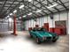 Spacious garage featuring a vehicle lift, classic car, and tool storage at 3465 Covington Trl, Mebane, NC 27302