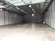 Expansive garage interior featuring concrete floor, metal walls, industrial lights, and a roll-up door at 3465 Covington Trl, Mebane, NC 27302