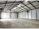 Vast garage interior with concrete floor, metal walls, multiple roll-up doors, and industrial lighting at 3465 Covington Trl, Mebane, NC 27302