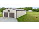 Outbuilding has two-bay garage with metal roof on a property with trees and grassy lawn at 3465 Covington Trl, Mebane, NC 27302
