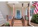 Inviting front porch with brick steps and posts, flowerpots, and a blue door with wreath at 347 Manchester Trl, Clayton, NC 27527