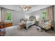 Neutral bedroom features carpeted floors, two windows, a bed with an iron frame, and an accent chair at 4 Barkridge Ct, Durham, NC 27713