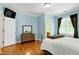 This bedroom has light blue walls, light wood floors, and a TV mounted in the corner at 404 Settlecroft Ln, Holly Springs, NC 27540