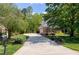 Elegant brick home with a circular driveway, well-manicured landscaping, and mature trees at 404 Settlecroft Ln, Holly Springs, NC 27540