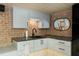 Stylish kitchenette with grey cabinetry, granite countertops, and a sink, complemented by brick wall accents at 404 Settlecroft Ln, Holly Springs, NC 27540