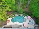 Aerial view of the backyard pool with an expansive patio and cozy lounge area surrounded by lush greenery at 404 Settlecroft Ln, Holly Springs, NC 27540