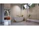 Bright bathroom showcasing a soaking tub, three windows, neutral tile, and stylish fixtures at 404 Shinleaf Pond Trl, Raleigh, NC 27614
