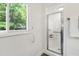 Bright bathroom with a glass-enclosed shower, grab bar, and window offering a view of the trees at 4213 Oak Park Rd, Raleigh, NC 27612