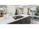 Kitchen featuring an island with a cooktop, marble countertops, dark cabinets and sliding doors to the outside at 4213 Oak Park Rd, Raleigh, NC 27612