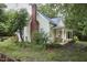 Charming exterior featuring a porch with swing beneath a large tree, and a brick chimney at 501 N Greensboro St, Carrboro, NC 27510