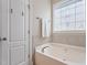 Bathroom with a soaking tub, decorative window and door with chrome hardware at 518 Spruce Meadows Ln, Willow Springs, NC 27592