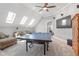 Large bonus room with ping pong table, mounted TV, and comfortable seating area under skylights at 518 Spruce Meadows Ln, Willow Springs, NC 27592