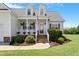 Inviting front porch with brick steps, classic white columns, lush landscaping, and a decorative American flag at 518 Spruce Meadows Ln, Willow Springs, NC 27592