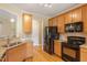 Well-lit kitchen featuring wood cabinets, granite countertops, and modern, black appliances at 518 Spruce Meadows Ln, Willow Springs, NC 27592