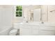 Bright bathroom featuring a double sink vanity, toilet, bathtub, and large window at 6521 Cablewood Dr, Raleigh, NC 27603