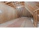 This attic features exposed wood framing, plywood flooring, and a small amount of light at 677 Juliette Ct, Creedmoor, NC 27522