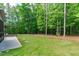 Lush backyard with stone patio, pergola, and access to mature trees and wooded area at 677 Juliette Ct, Creedmoor, NC 27522